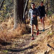 two people running on a trail in the fall