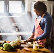 young black man chopping vegetables while preparing food in the kitchen copy space